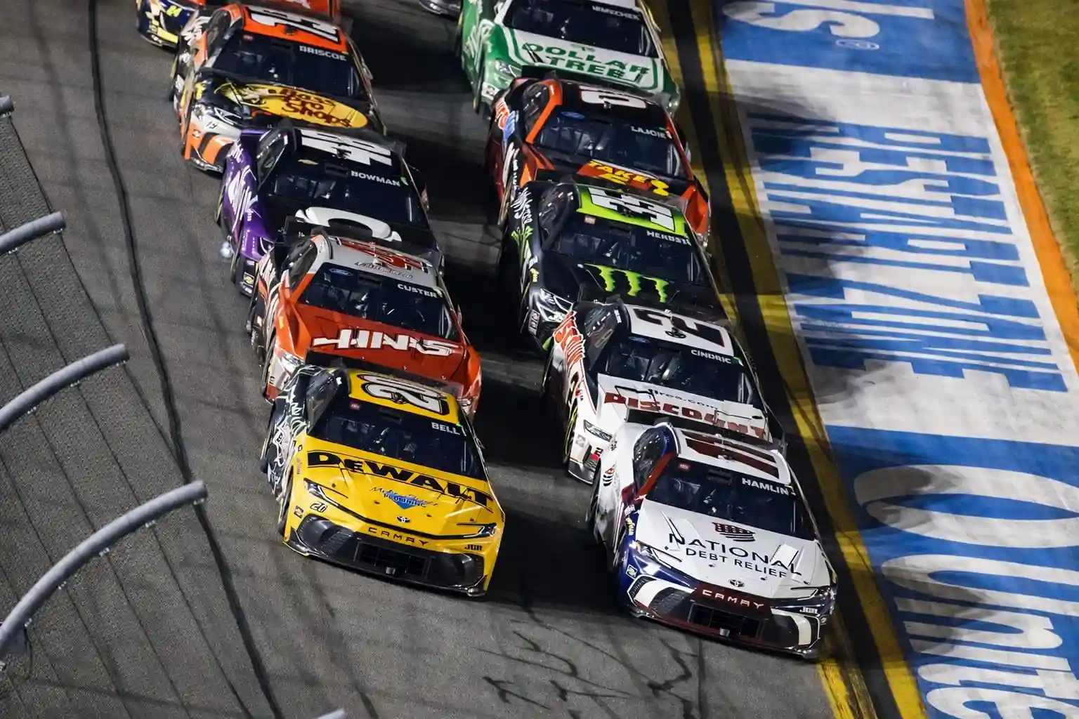 NASCAR stock cars race side-by-side on the track during a Daytona 500 event