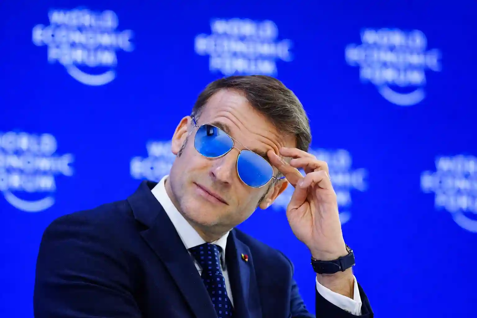 French President Emmanuel Macron adjusting his sunglasses at the World Economic Forum.
